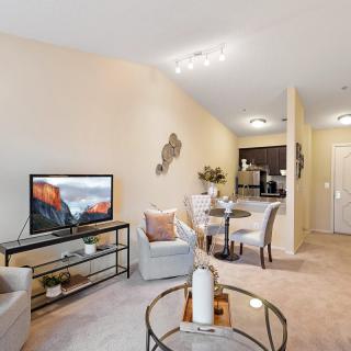 A modern and cozy living room with a TV, seating area, and a small dining space.
