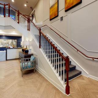A spacious interior lobby featuring a staircase with wooden railings and modern artwork on the walls.