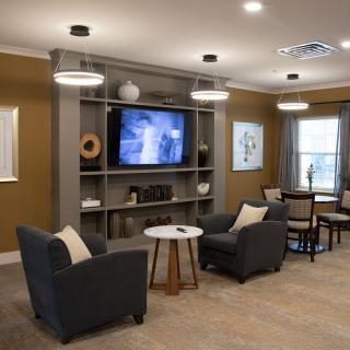 A modern living room with comfortable seating and a large television, featuring stylish decor and warm lighting.