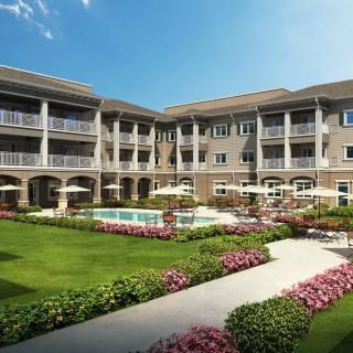A beautifully landscaped residential apartment building with a garden and pool.