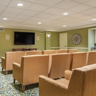 A cozy theater room with multiple rows of seating and a large television on the wall.
