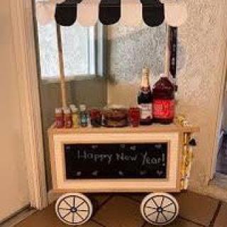 A decorative drink cart set up for a celebration with assorted beverages and snacks.