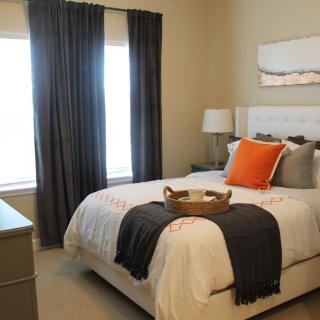 A modern and cozy bedroom with a neatly made bed, dark curtains, and stylish decor.