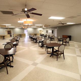 A spacious dining area with tables and chairs, featuring ceiling fans for airflow.