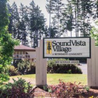 Entrance sign for Sound Vista Village, a retirement community surrounded by trees.
