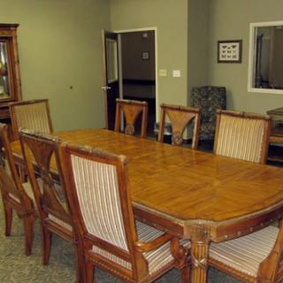 A dining room with a large wooden table and matching chairs.
