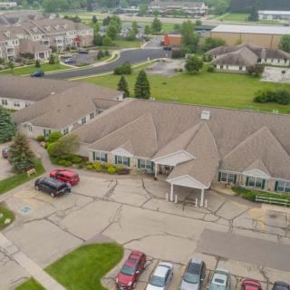 Aerial view of a suburban residential building with a parking lot and surrounding greenery.