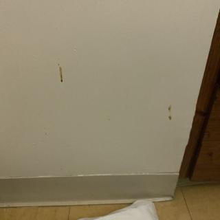 A white wall with visible scuffs and scratches near the floor.
