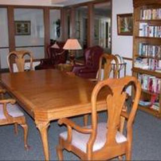 A cozy library room with a wooden table, chairs, and bookshelves.