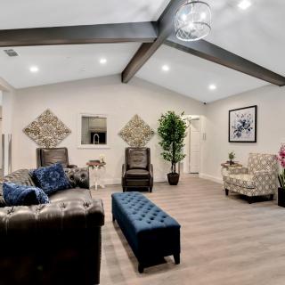 A modern living room featuring comfortable furniture, decorative plants, and stylish artwork under exposed ceiling beams.