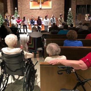 A group of people watching a performance in a church setting, with Christmas decorations.