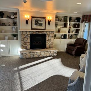 A cozy living room featuring a stone fireplace, surrounded by built-in bookshelves and an armchair.