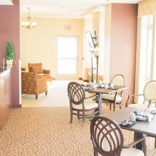 A bright and elegant dining area with neatly arranged tables and chairs, featuring warm lighting and tasteful decor.