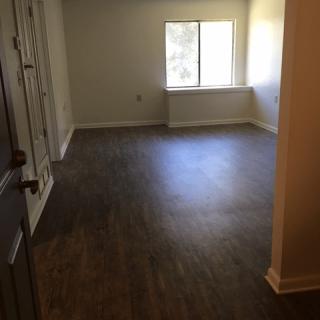 An empty room with hardwood flooring and a window letting in natural light.