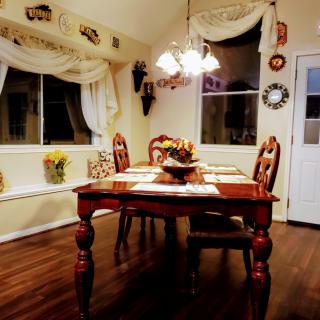 A cozy dining room with a wooden table set for guests, illuminated by a chandelier.