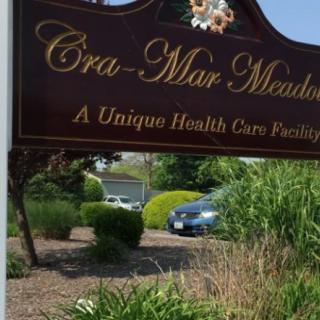 Sign for Cra-Mar Meadows, a unique healthcare facility, surrounded by landscaping.