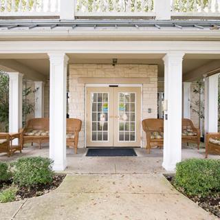 A welcoming porch entrance with wicker furniture and white columns.