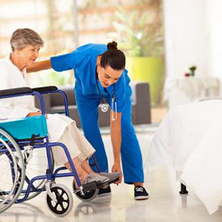 A healthcare professional assists an elderly patient in a wheelchair, demonstrating the importance of compassionate care.