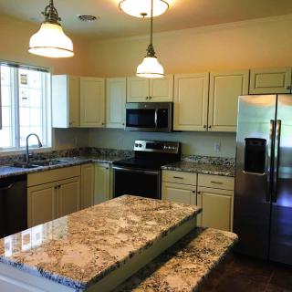 A modern kitchen with granite countertops and stainless steel appliances.
