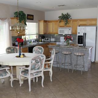 A cozy kitchen and dining area featuring a round table with chairs, barstools at the counter, and various kitchen appliances.
