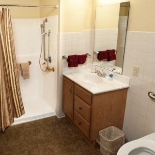 A clean and organized bathroom with a shower, sink, mirror, and toilet.