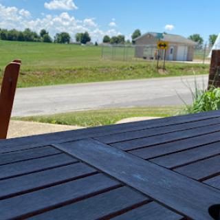 A peaceful outdoor setting featuring a wooden table, with a rural landscape and blue sky in the background.