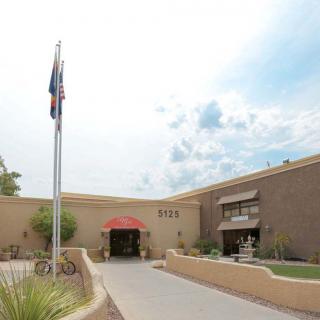 A building entrance with a flagpole and a clear, cloudy sky.