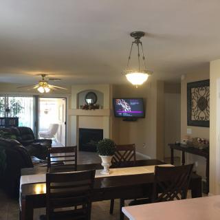 A cozy living and dining area featuring a TV mounted above a fireplace.