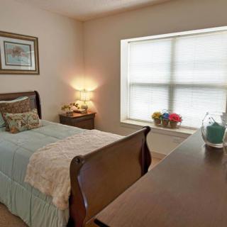 A cozy bedroom with a single bed, nightstand, and soft lighting.