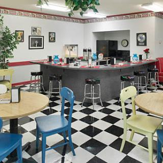 A vibrant diner interior featuring colorful chairs and a classic black and white tiled floor.