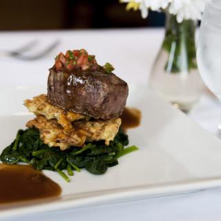 A gourmet steak dish elegantly plated with spinach and sauces.