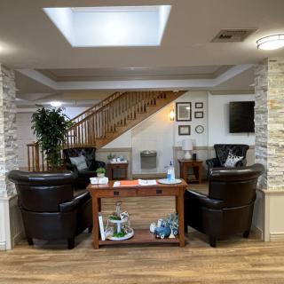 A cozy waiting area featuring leather chairs and a wooden staircase.