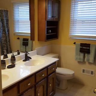 A tidy bathroom featuring wooden cabinets, a double sink with mirrors, and neatly arranged towels.