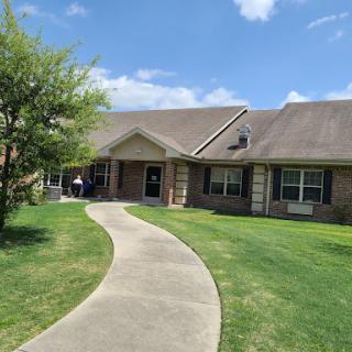 A charming residential home with a well-maintained lawn and clear blue sky.