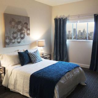 A modern bedroom featuring elegant decor with blue accents and natural lighting.