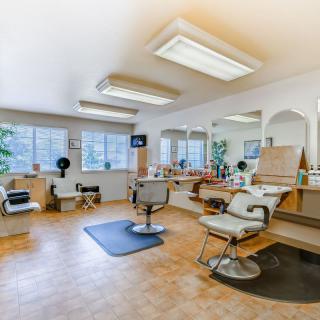 A spacious barber shop interior with chairs and mirrors.