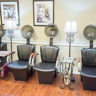 A cozy salon interior featuring hair dryers and comfortable seating.