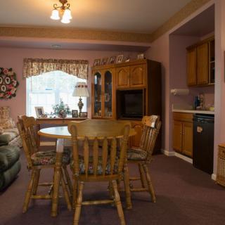 A cozy dining area with wooden furniture and a kitchen in the background.