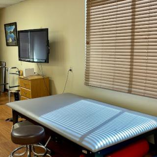 A clean and organized treatment room in a healthcare facility, equipped with a patient bed and a television monitor.