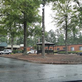 A view of a rainy parking lot surrounded by trees and buildings.