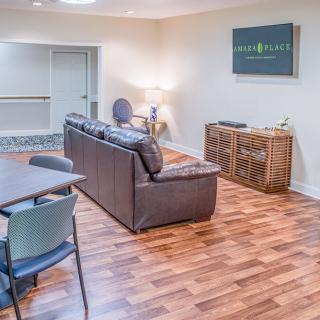 A modern living room with a sofa, wooden flooring, and a small dining table.