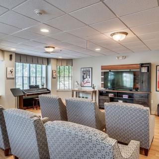 A cozy home theater setup featuring comfortable seating, a large TV, and a music keyboard.