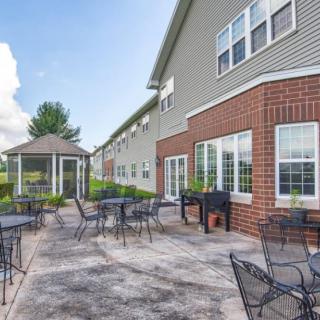 An outdoor patio area with tables and chairs next to a building, featuring a gazebo in the background.