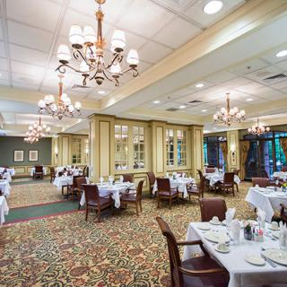 An elegant restaurant dining room with chandeliers and tables set with white tablecloths.