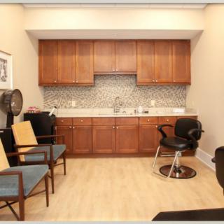A cozy salon interior with chairs, a sink, and wooden cabinets.