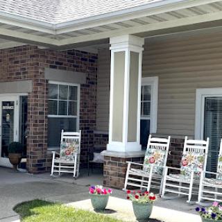 A serene outdoor porch featuring rocking chairs and potted flowers, perfect for relaxation.