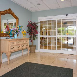 A welcoming lobby entrance with a dresser, mirror, and decorative plants.