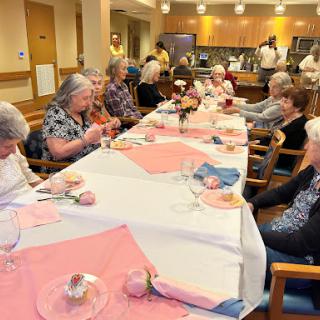 A joyful gathering of seniors enjoying a meal together in a communal dining space.