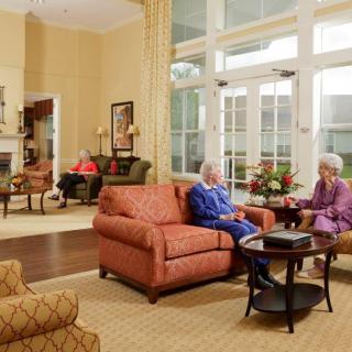 A cozy living room with elderly individuals engaging in conversation and relaxation.