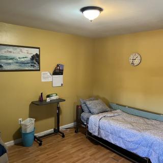 A simple bedroom with yellow walls, featuring a single bed and wall decorations.